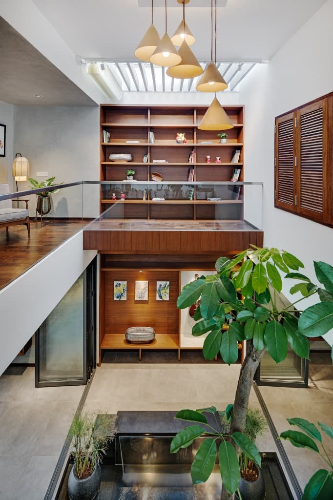 Central atrium vista looking across the reflective indoor water court toward the full-height teak bookcase