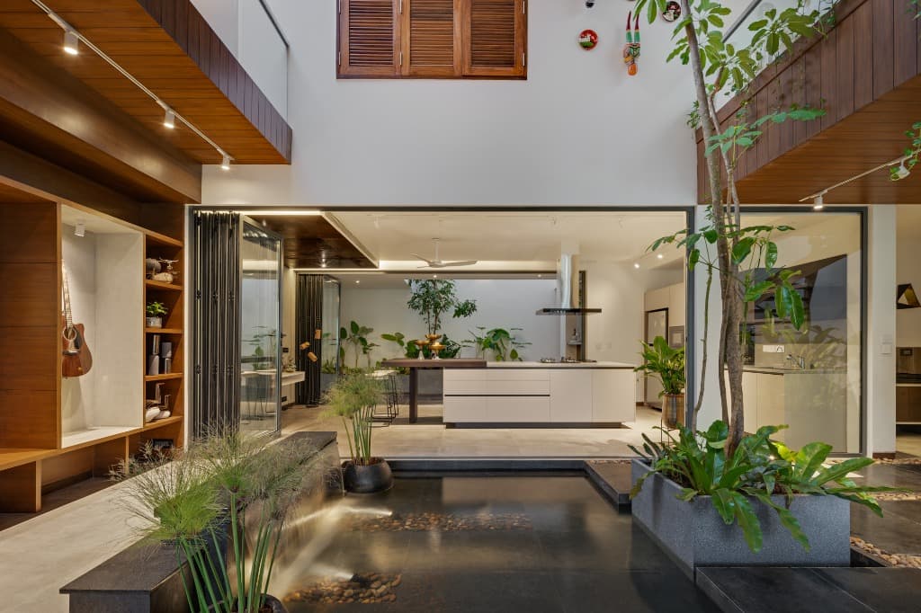 Panoramic ground-level view connecting the cascading waterfall basin to the culinary pavilion and indoor tree