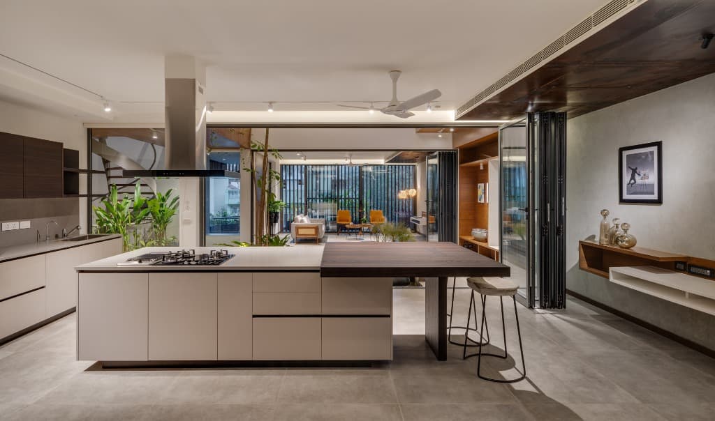 Gourmet open kitchen featuring a monolithic island, integrated cooktop, and cantilevered solid timber dining counter