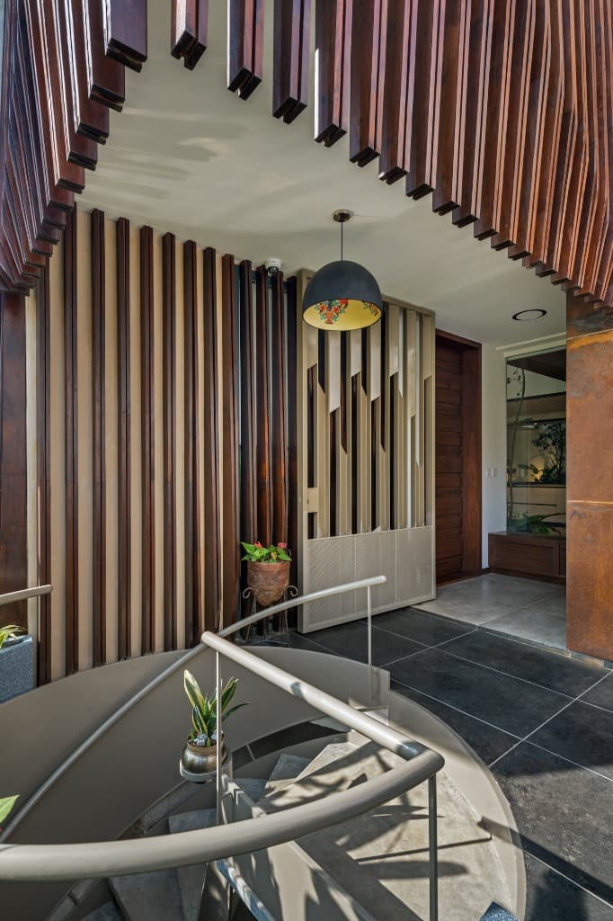 Sculptural spiral staircase arrival foyer accented by parametric timber batten canopy