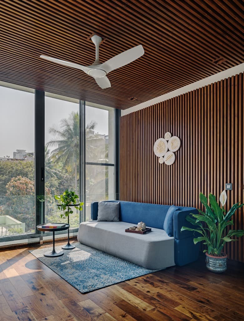 Upper level reading lounge featuring full-height acoustic timber battens, custom sofa, and panoramic tree canopy views