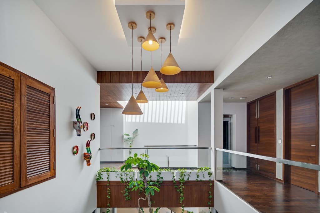 Upper floor glass-and-timber walkway bridge overlooking the central atrium with wood louvered shutters