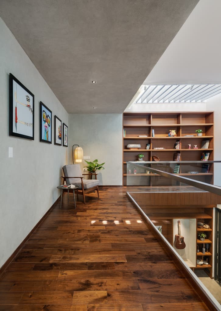 Upper floor library gallery with teak hardwood floors, exposed concrete ceiling, curated pop-art wall, and reading nook
