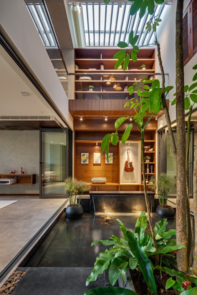 Double-height atrium featuring a built-in acoustic guitar display niche and Kadappa stone waterfall cascade