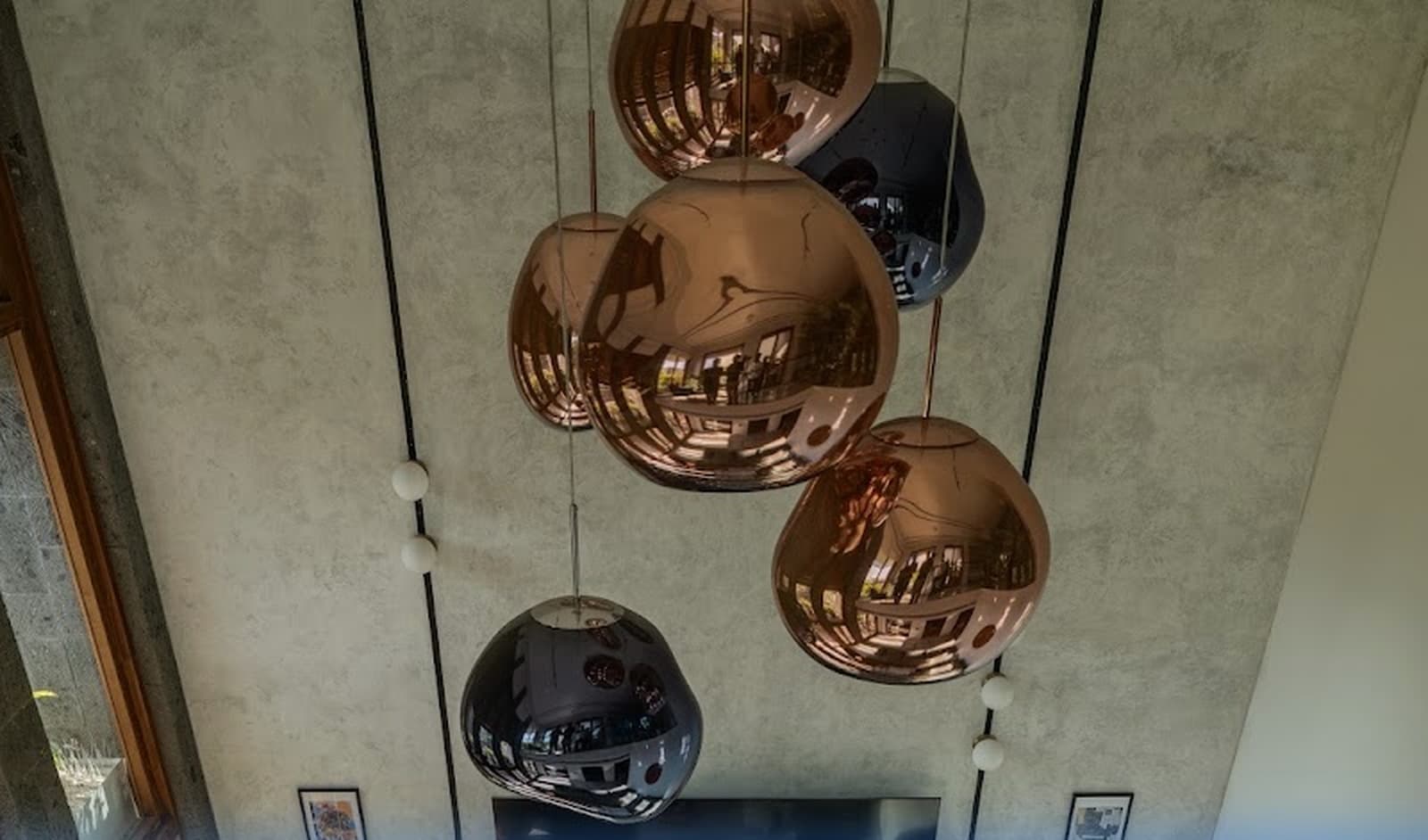 Dramatic double-height living atrium with reflective Tom Dixon style copper and chrome cluster pendant light installation