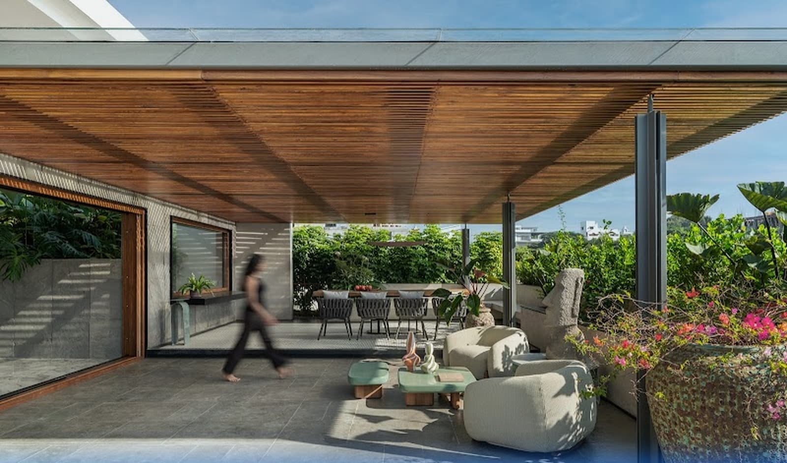 Covered outdoor veranda and terrace lounge framed by a slatted timber ceiling, designer seating, and flourishing gardens