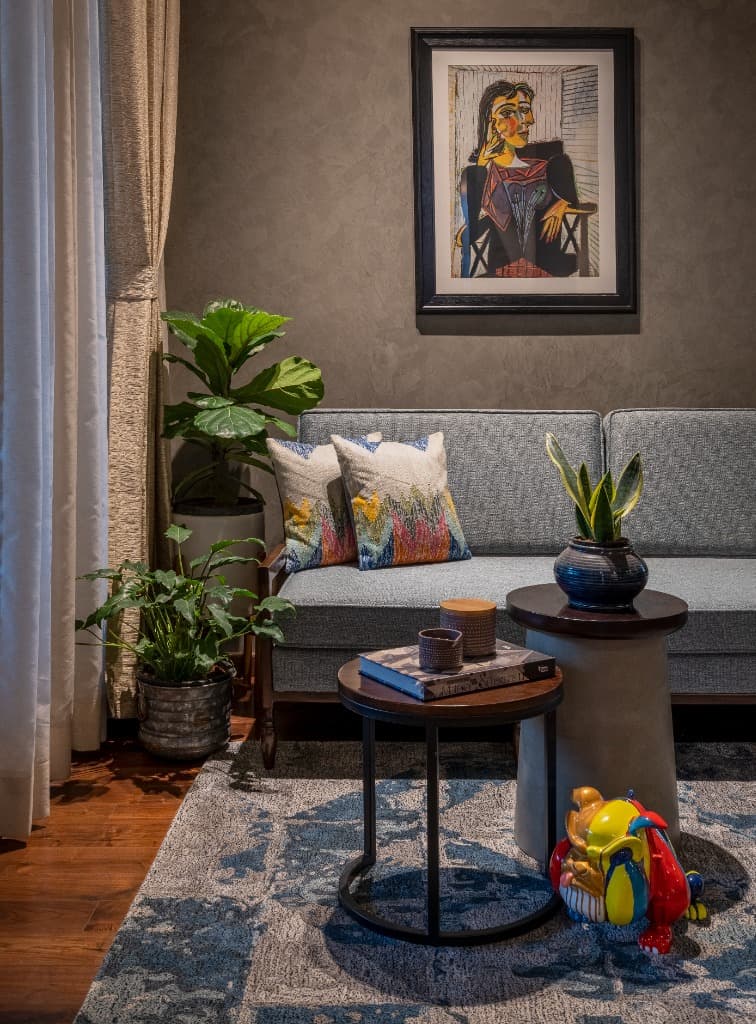 Intimate bedroom sitting lounge featuring tailored grey sofa, artisanal embroidered cushions, and potted fiddle-leaf fig