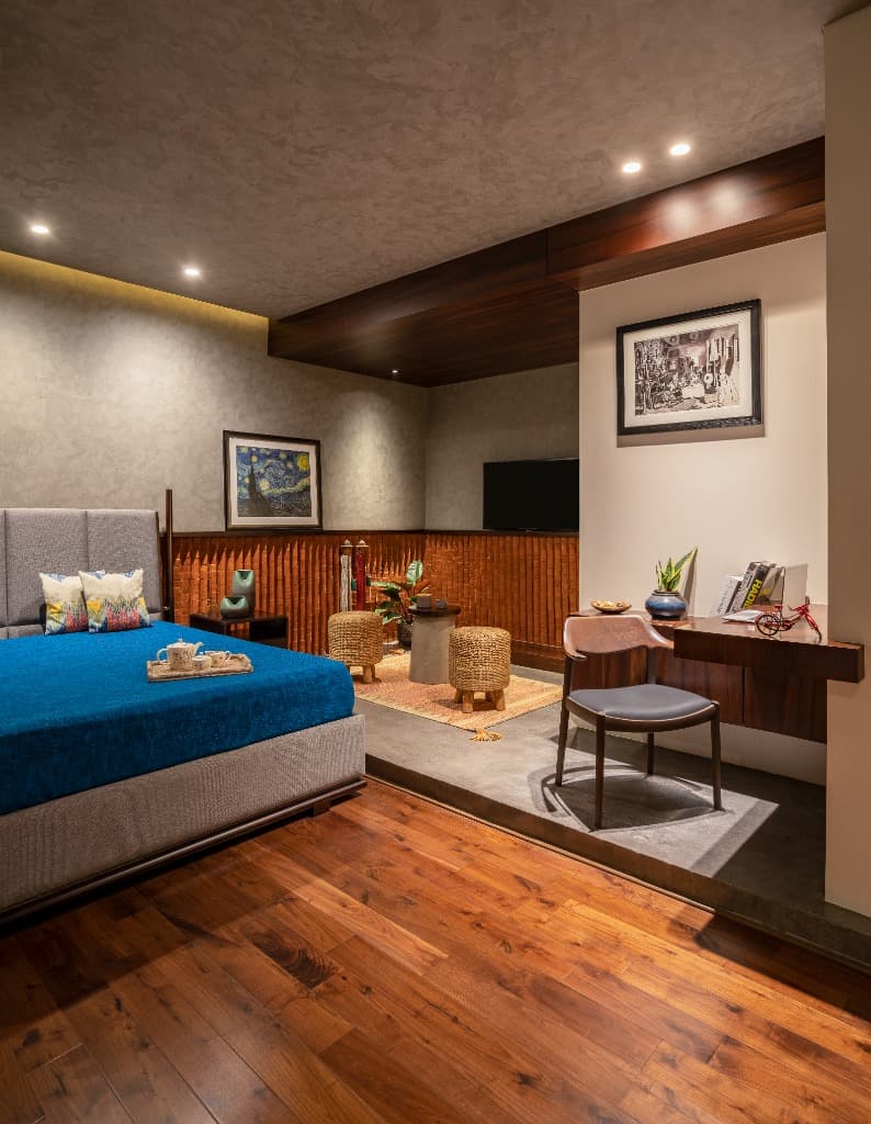Guest bedroom suite featuring solid hardwood flooring, fluted brick acoustic wall, upholstered bed, and bespoke cantilevered study desk