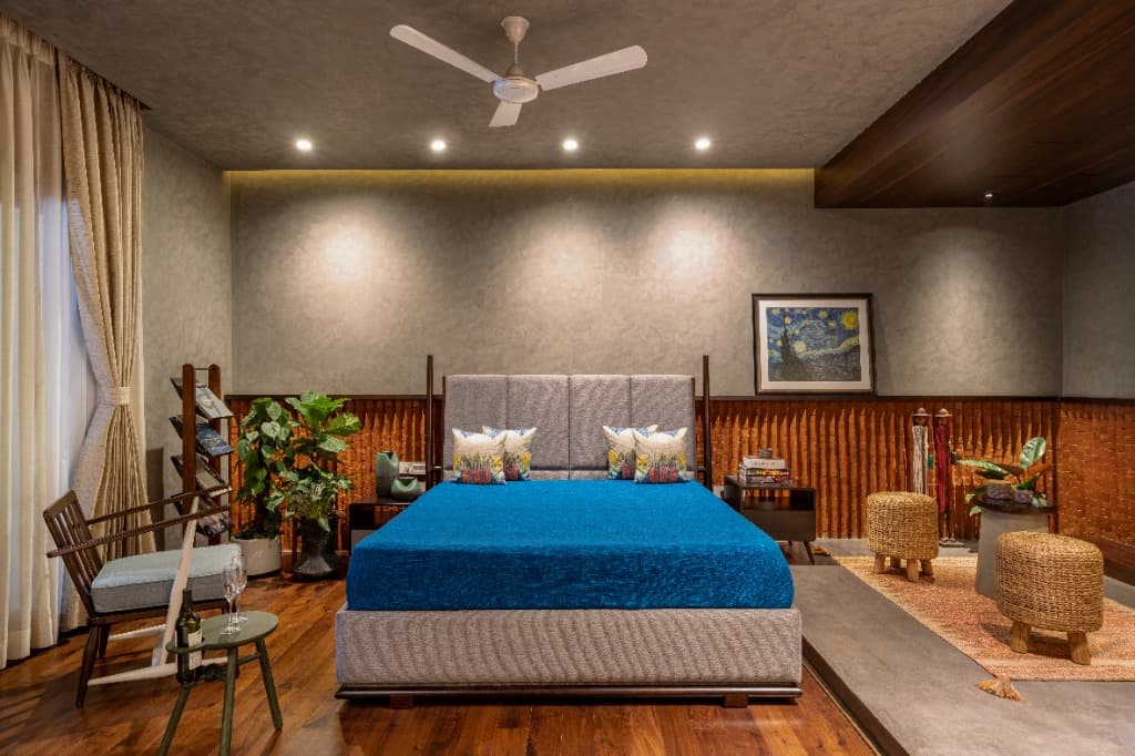 Spacious bedroom suite showcasing fluted terracotta acoustic wainscoting, limewash walls, upholstered bed in cobalt blue, and mid-century furnishings