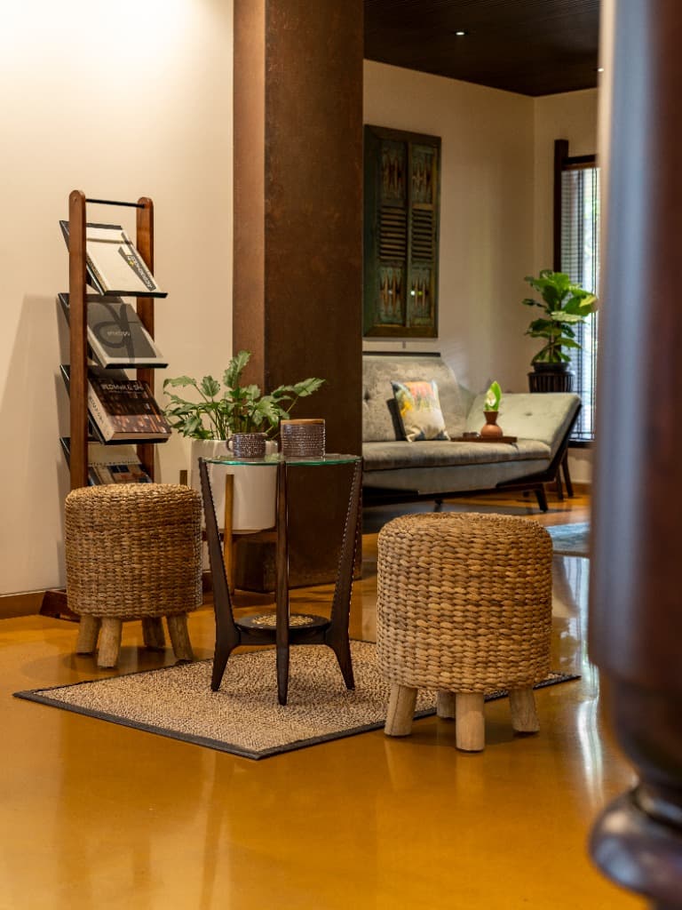 Artisanal woven rattan stools, teak magazine stand, and tactile rust-toned pillar detail