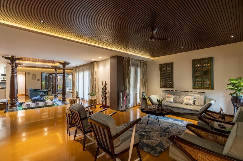 Wide perspective of the formal lounge with acoustic fluted ceiling, looking across ochre stone floors to the mandapa court