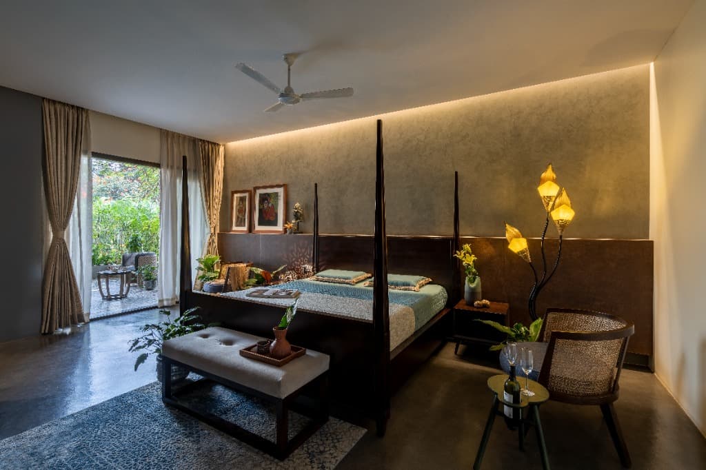 Expansive master suite with four-poster bed opening directly through sliding glass doors to a private landscaped courtyard terrace