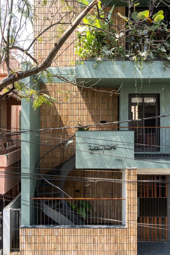 Mid-level perspective of the arrival terrace featuring the external spiral staircase, Kannada house inscription, and slatted security grilles