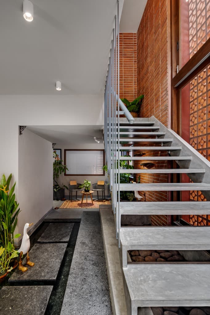 Entry foyer leading over black granite stepping stones across an indoor reflecting pool to the concrete staircase and terracotta jali screen
