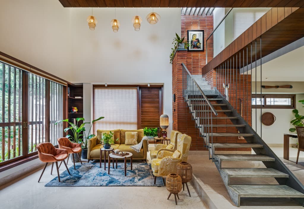 Spacious main living lounge featuring mustard seating, exposed brick column with curated art, and floor-to-ceiling timber louvered fenestration