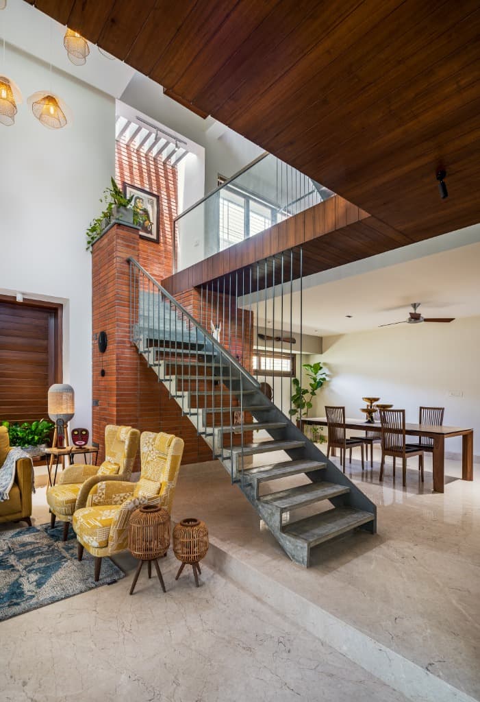 Floating concrete staircase acting as a sculptural divider between the intimate living lounge and open dining room