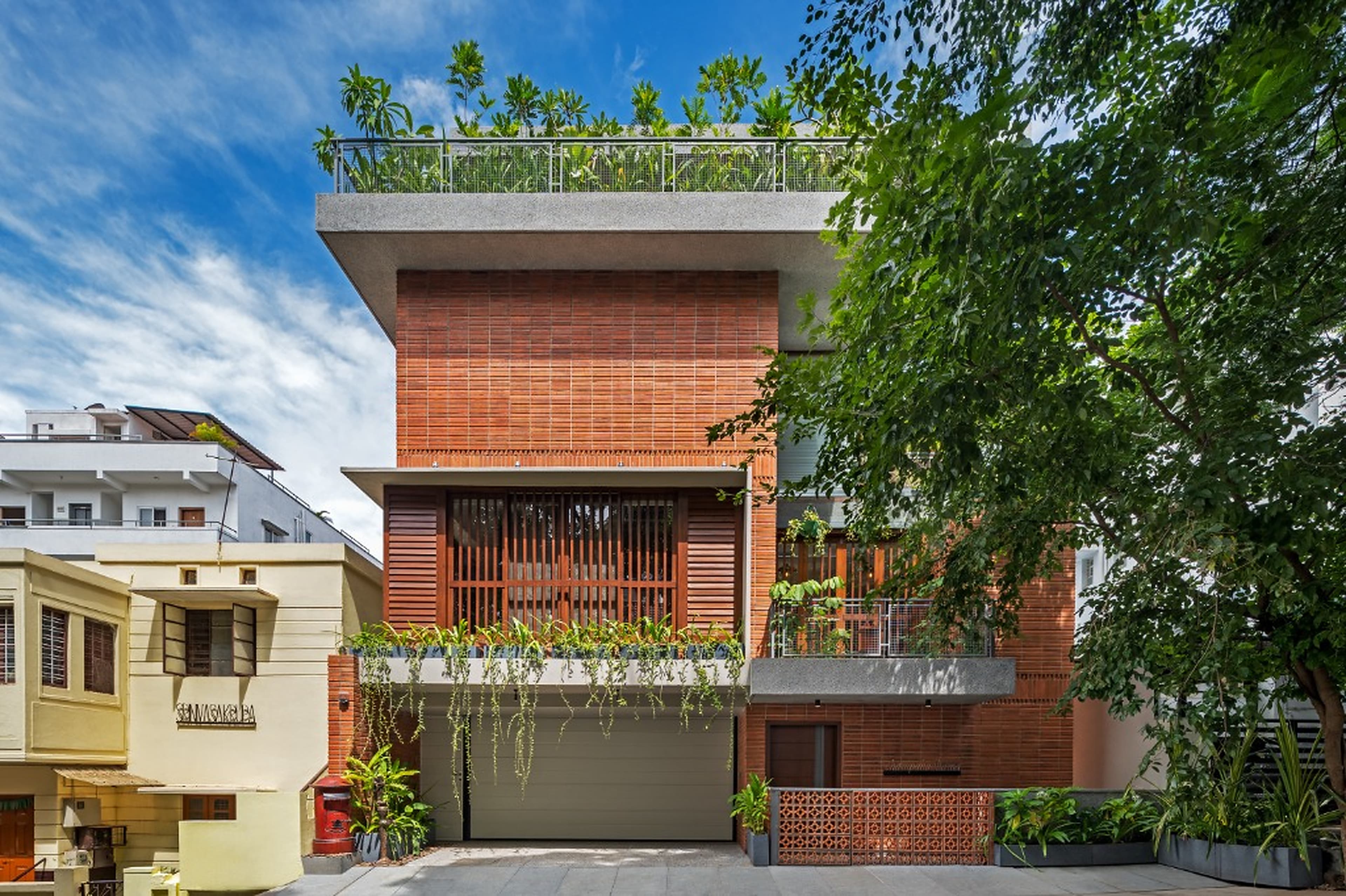 Full contextual street elevation nestled in the neighborhood, featuring ground-floor garage, timber bay screen, and rooftop garden