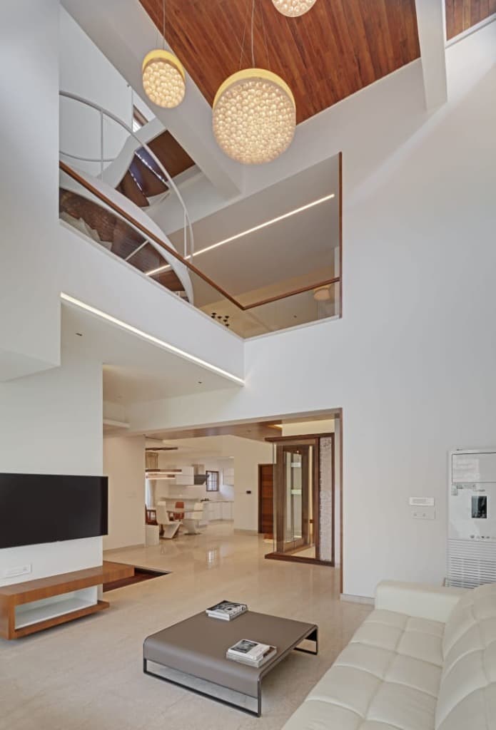Double-height living salon overlooking the helical spiral staircase, suspended luminous pendants, and open plan ground level