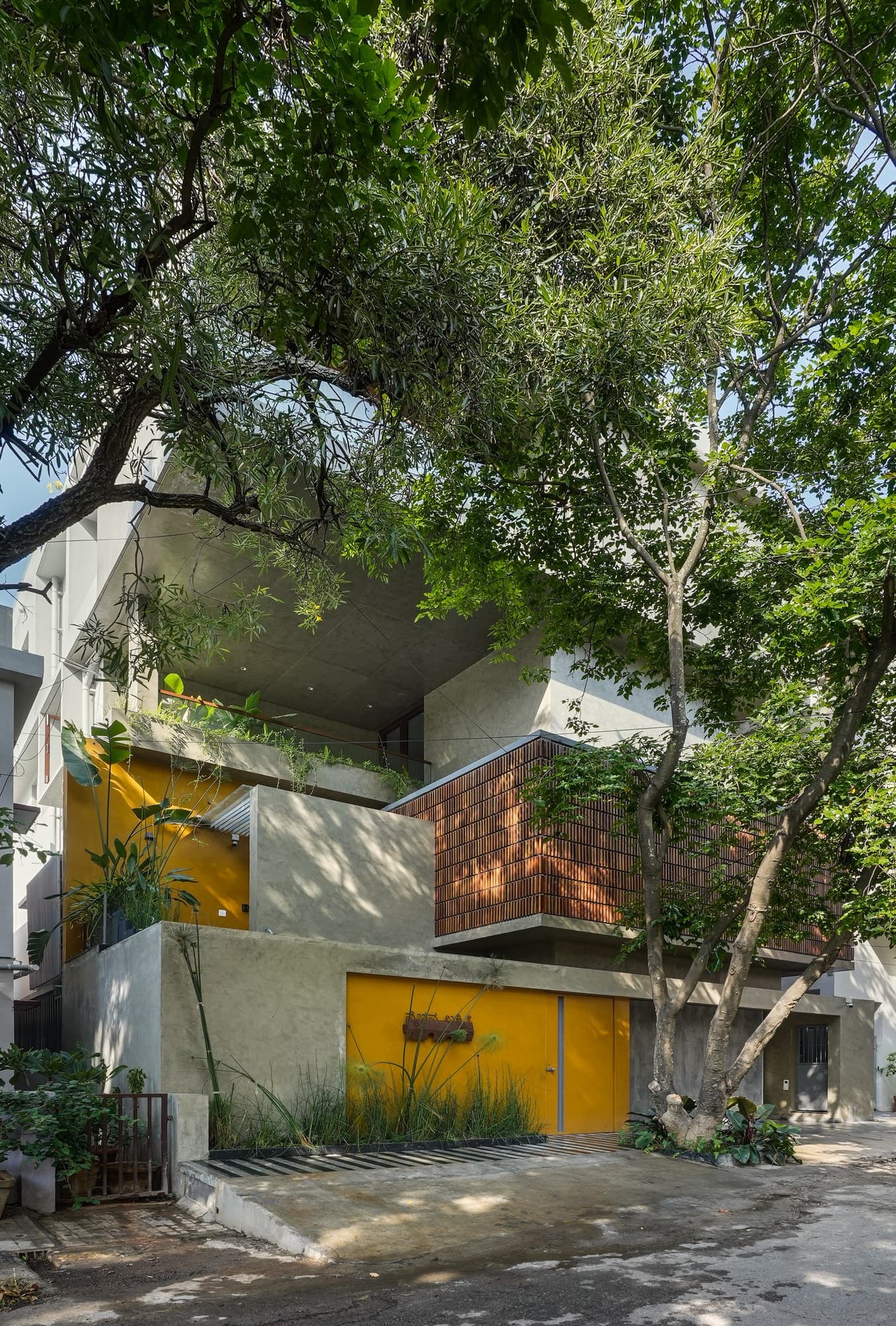 Framed entrance portico with vibrant yellow portal and teak door