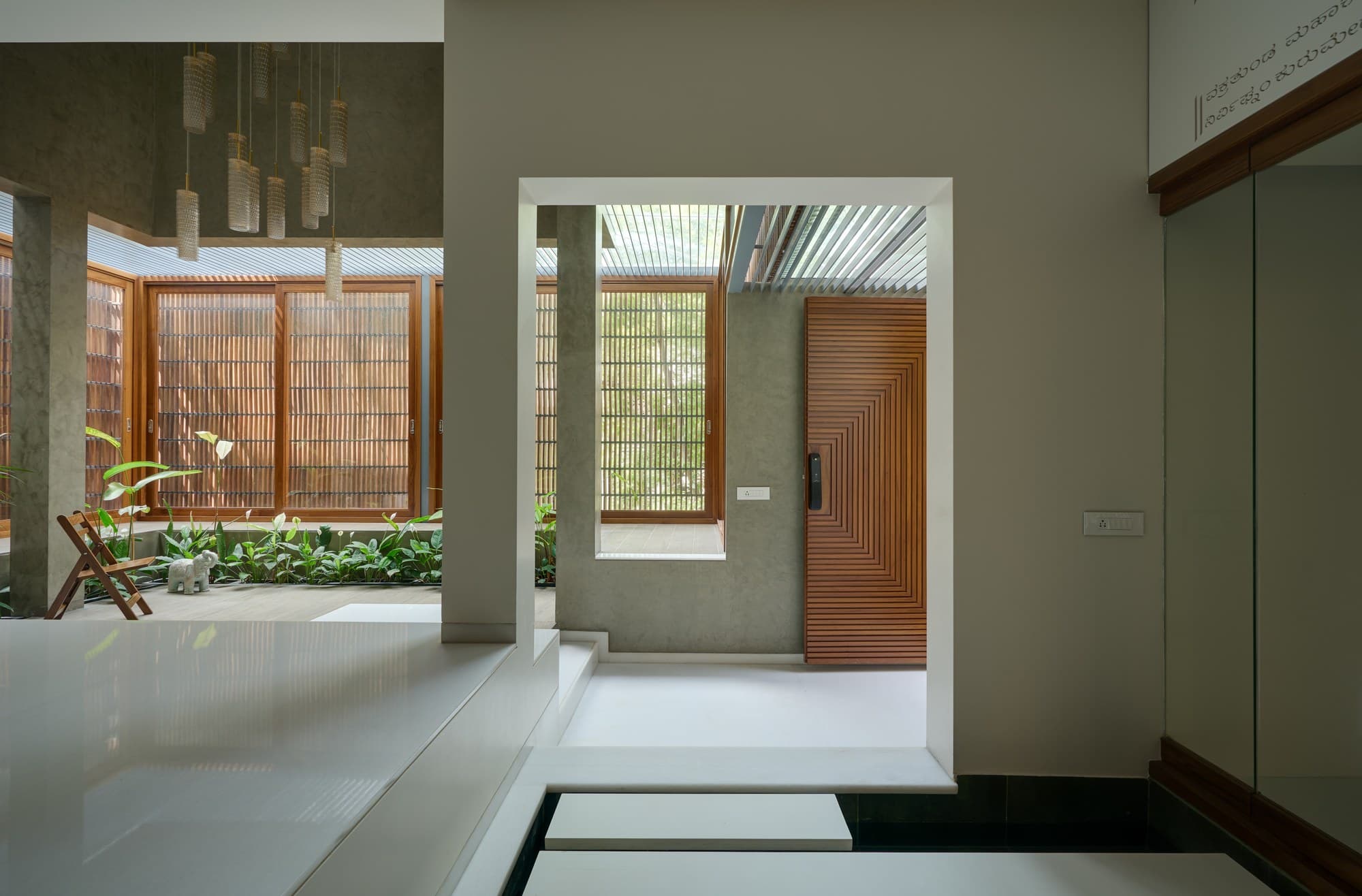 Foyer arrival threshold with chevron-carved teak door and water channel steps
