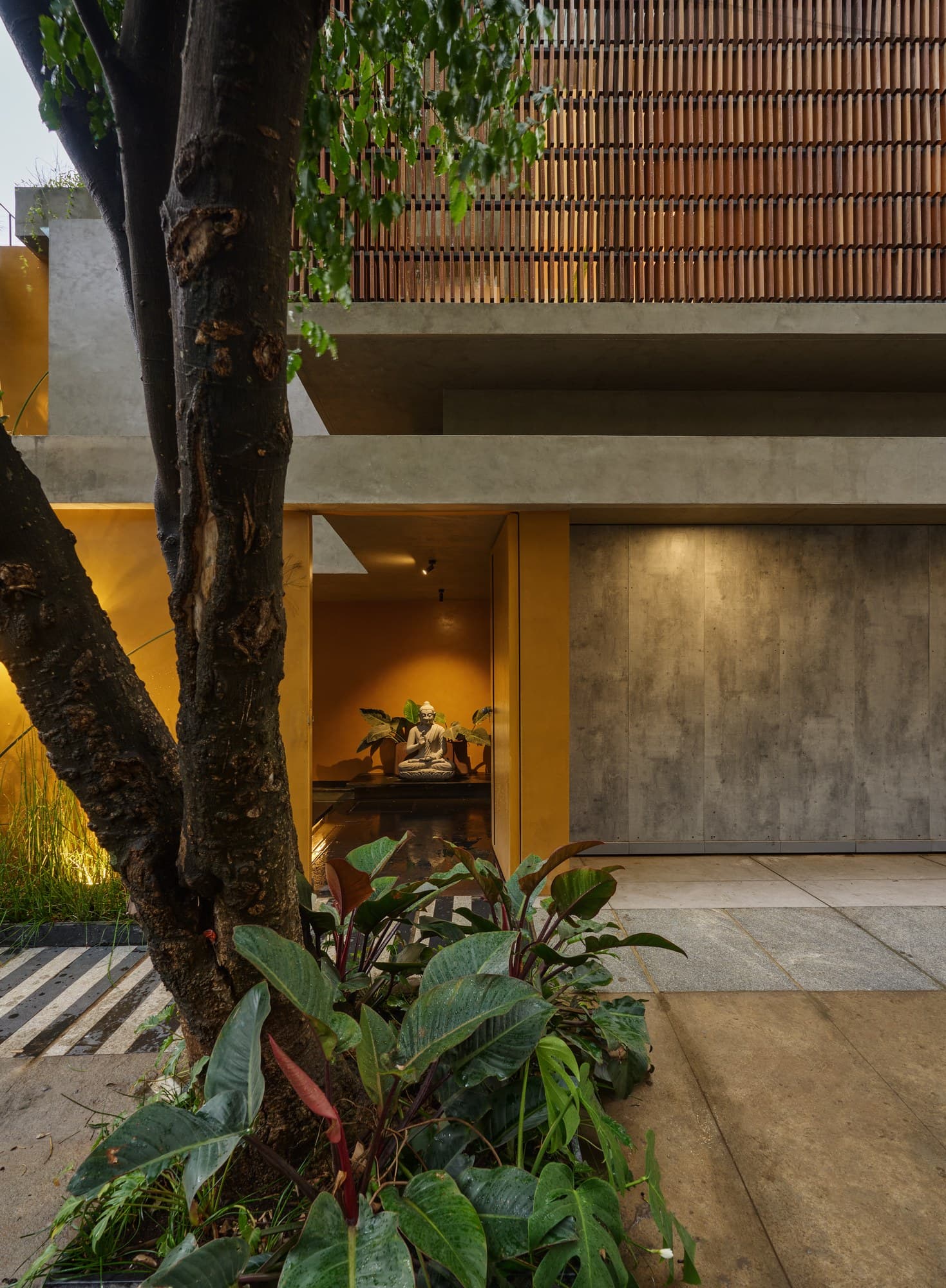 Entry courtyard framed by lush perimeter greenery and fair-faced concrete walls
