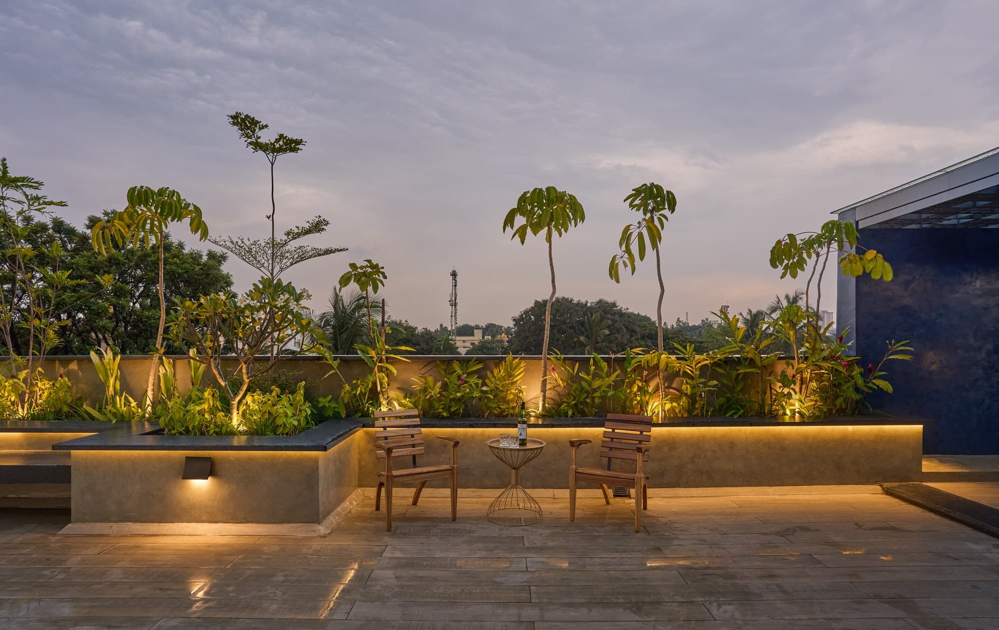 Rooftop deck at dusk with ambient lit planter seating and skyline panorama